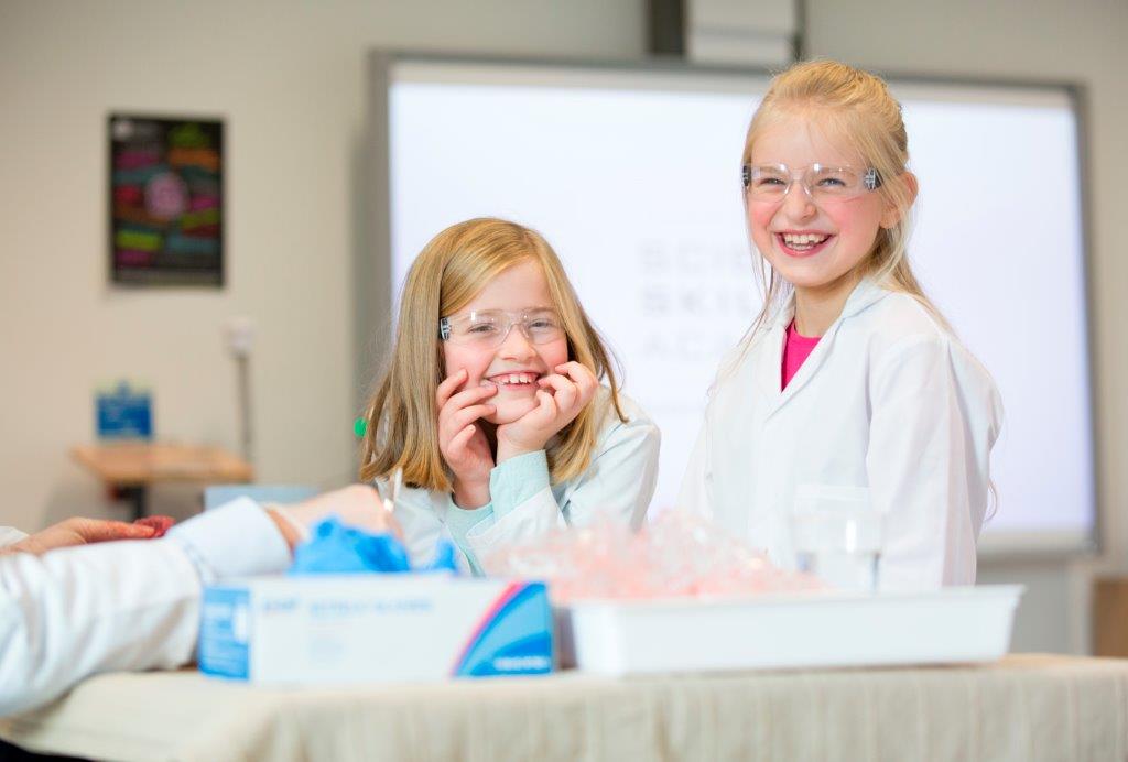 Two happy children in lab coats at the Science skills academy